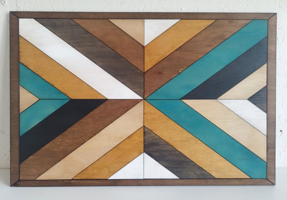 Panneau décoratif en bois aux motifs géométriques beige, marron, turquoise et noir.